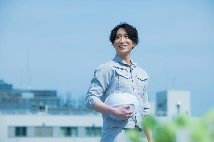 ヘルメットを持つ作業着姿のスタッフ